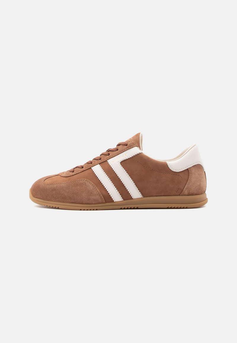 Καφέ σουέντ αθλητικό παπούτσι με λευκές δερμάτινες ρίγες και ταμπά πλευρά στη φτέρνα, μπεζ λαστιχένια σόλα και κλείσιμο με κορδόνια, εμφανίζεται από το πλάι σε λευκό φόντο.