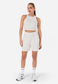 White ribbed crop top and matching high-waisted shorts, featuring an elastic waistband. Worn with white sneakers and patterned socks.
