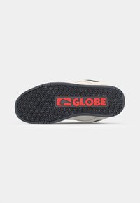 Sneaker outsole with a textured black rubber grip, featuring a red "GLOBE" logo and a smooth light gray upper section.