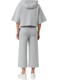 Gray cropped hoodie with wide sleeves and a hood, paired with high-waisted, wide-legged gray pants. White sneakers complete the outfit.