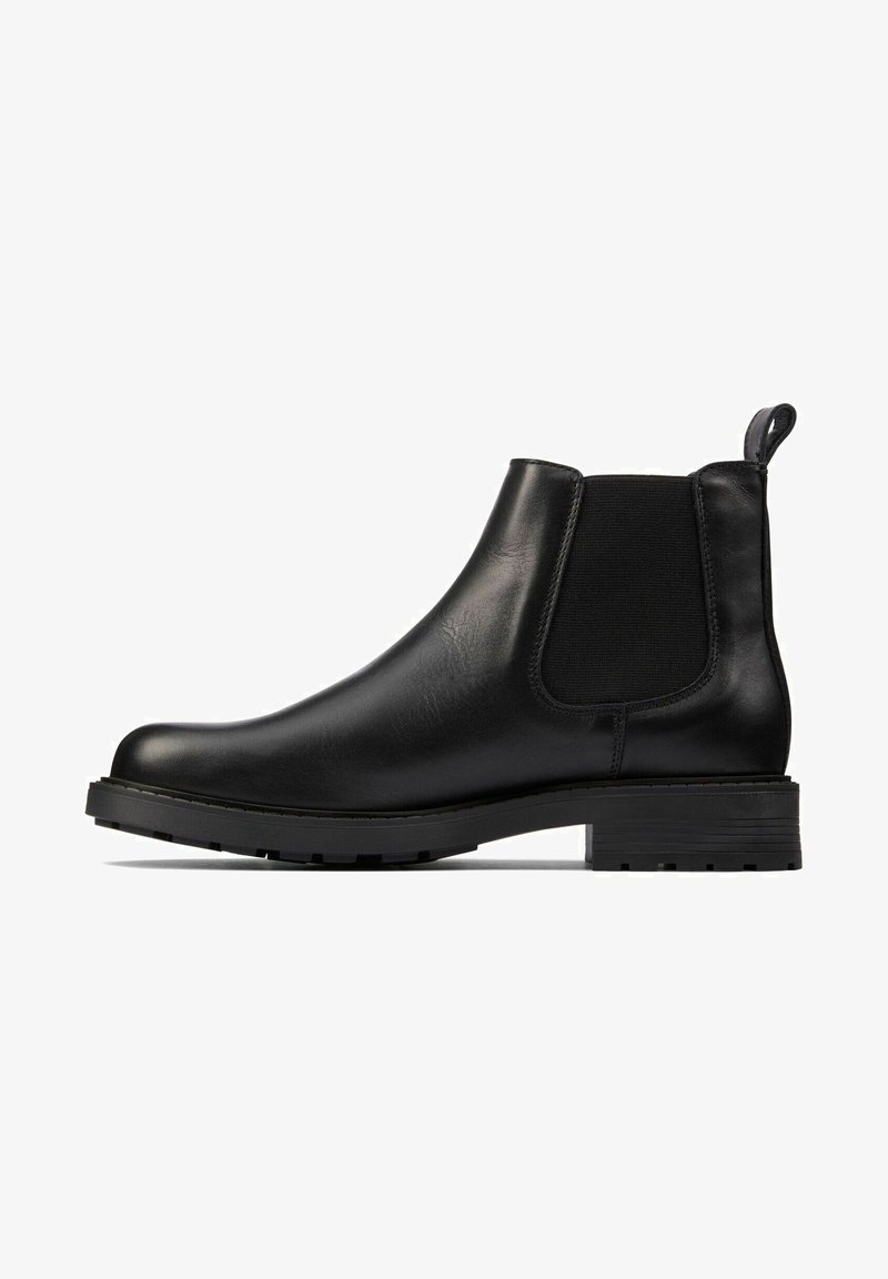 Botas Chelsea de couro preto com painéis elásticos laterais, bico arredondado e uma alça de puxar. Sola de borracha com relevos para melhor aderência e durabilidade.