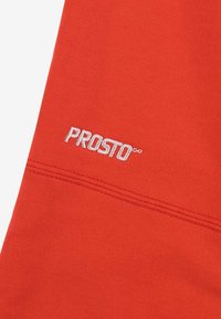 Czerwona rozciągliwa góra z białym logo "PROSTO". Charakteryzuje się gładką fakturą i płaskim szwem, podkreślając czysty, nowoczesny design.