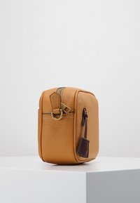 Brązowa skórzana torba o fakturowanej powierzchni, prostokątnym kształcie, froncie zapinanym na zamek oraz złotych elementach ozdobnych z ciemnobrązową metką.