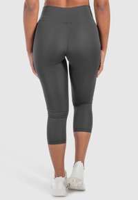 Leggings capri grigio scuro con un'alta vita, realizzati in materiale elasticizzato, caratterizzati da una texture liscia e senza motivi o dettagli visibili.