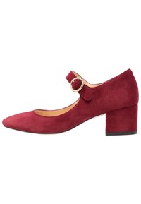Chaussure en daim rouge à talon moyen avec un bout pointu, une bride à la cheville avec une boucle dorée, et une finition texturée sur la tige.