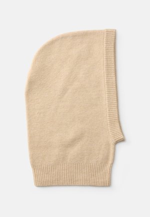 Beige stickad mössa med ribbad kant och rundad topp, tillverkad av mjukt material. Har en asymmetrisk design för en snug passform.