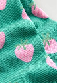 Grüner Stoff mit einer gerippten Textur und rosa Erdbeermuster. Jede Erdbeere hat grüne Blätter und kleine weiße Samen.