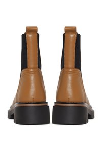 Paire de bottines en cuir beige avec panneaux latéraux élastiques noirs et semelles épaisses en caoutchouc noir vues de dos.