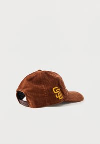 Brown corduroy cap with a yellow "SD" logo on the side and an adjustable strap. Curved brim and textured fabric design.