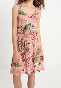 Vestido sin mangas de color rosa con un estampado floral que presenta hojas verdes y flores blancas, fruncido en la cintura, hecho de una tela ligera.