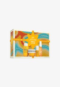 L'ensemble comprend un gel douche Brésilien, une crème Brésilienne Bum Bum et un parfum, tous dans des contenants jaunes. La boîte décorative présente un motif abstrait coloré.