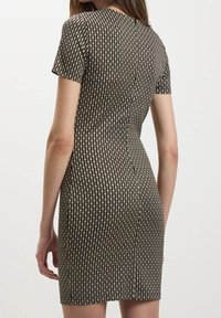 Robe noire moulante avec un motif texturé de petites formes ovales beige, manches courtes et col rond.