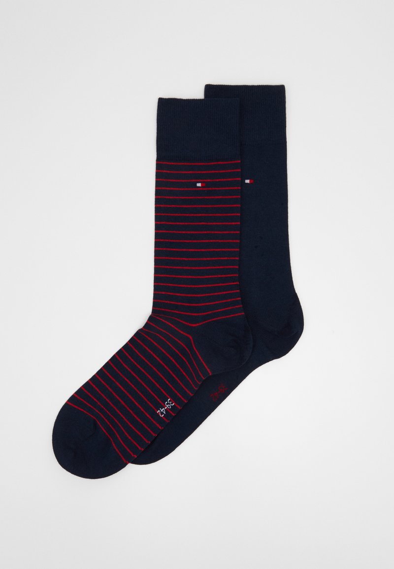 Calze blu navy con strisce rosse, una coppia con un colore solido, realizzate in materiale morbido; presentano un piccolo logo e colori a contrasto.