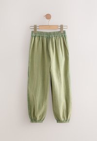 Light green fabric trousers with a textured stripe pattern, elastic waistband, and gathered cuffs, hanging on a wooden hanger.