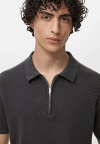 Polo negru cu textură, având un fermoar scurt și un design clasic de guler. Materialul pare a fi tricotat și respirabil.