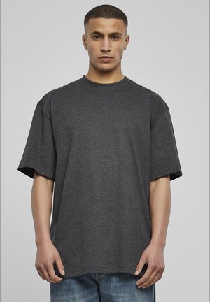 Tricou scurt cu mânecă scurtă, gri închis, cu o croială lejeră, decolteu rotund și textură moale, purtat cu blugi albaștri.