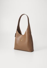 Sac cabas en cuir marron avec une seule bandoulière et un petit bouton rond doré sur la poche avant.