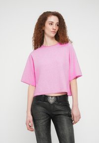 Φούξια κοντό τοπ με κοντά μανίκια, κατασκευασμένο από απαλό υλικό. Συνδυάζεται με μαύρο παντελόνι και ασημί αγκράφα ζώνης σε σχήμα καρδιάς.