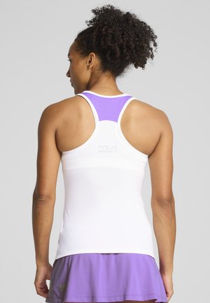 Donna vista di spalle che indossa una canottiera bianca con schiena a vogatore e inserto in mesh viola, abbinata a una gonna plissettata viola.