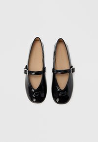Fekete lakkbőr balerina cipő kerek orral, ezüst csatos Mary Jane pánttal és párnázott bézs talpbéléssel.