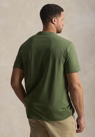 Λαδί πράσινο κοντομάνικο μπλουζάκι με στρογγυλή λαιμόκοψη, λεία υφή και πλαϊνές σχισμές, εμφανιζόμενο από πίσω όψη.