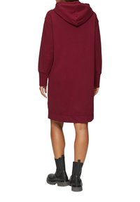 Burgunderfarbene Kapuzenkleid mit langen Ärmeln, aus solidem Stoff und seitlichen Taschen. Endet oberhalb des Knies mit geripptem Saum und Bündchen.