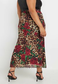 Falda maxi de estampado de leopardo con acentos de rosas rojas, tela transparente y dobladillo en forma de pico, con una cintura ajustada y una abertura lateral.