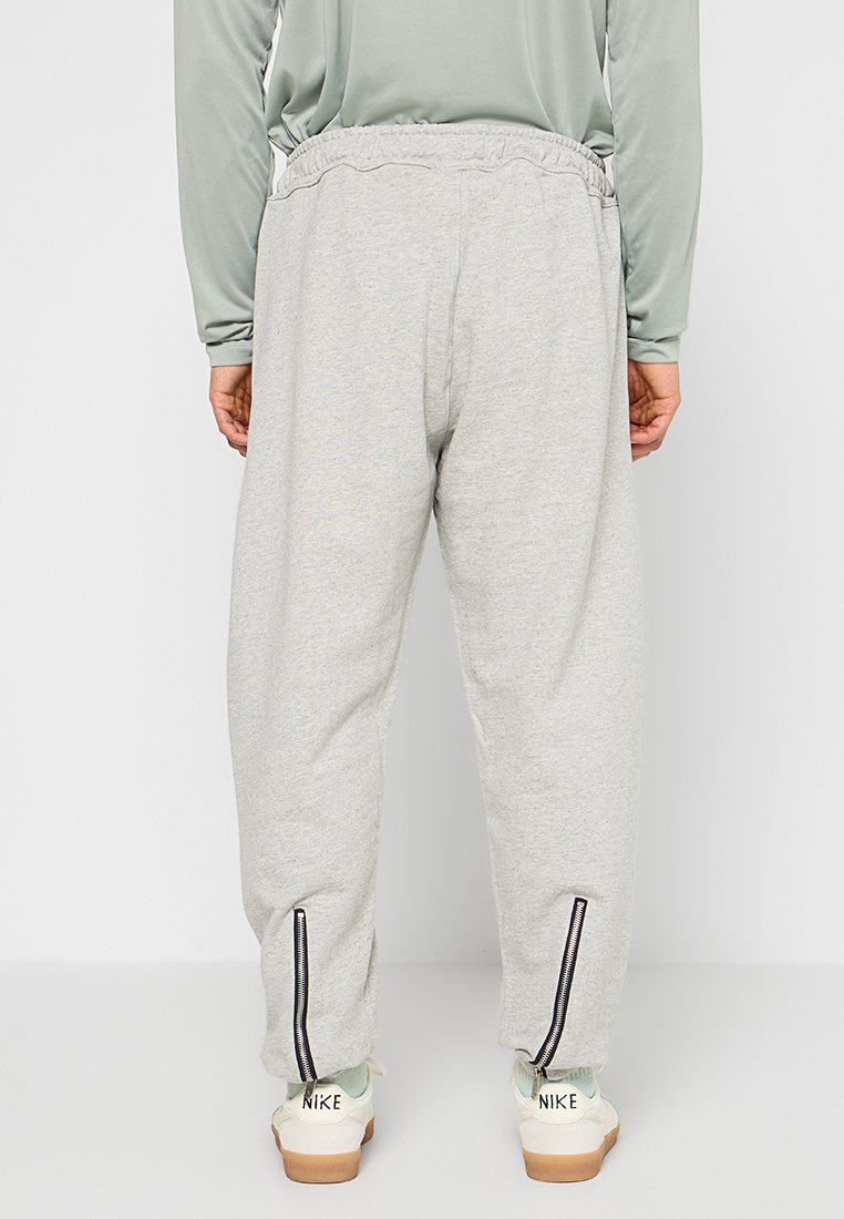 Pantalons de survêtement gris avec une coupe décontractée, une taille élastique et des zips sur les chevilles. Fabriqués en tissu doux et texturé.
