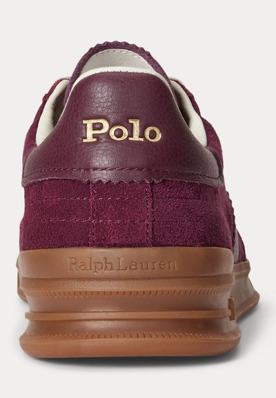 Bordo spalvos zomšiniai sportbačiai su odine kulno juostele, auksiniu „Polo“ logotipu ir ruda padais, kurioje įspaustas „Ralph Lauren“ ženklas.