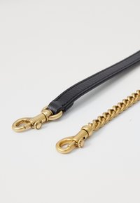 Schwarzer Lederriemen mit goldenen Beschlägen, ausgestattet mit einem geflochtenen Kettenabschnitt und zwei Drehkarabinern zur Befestigung. Glatte Textur und elegantes Design.