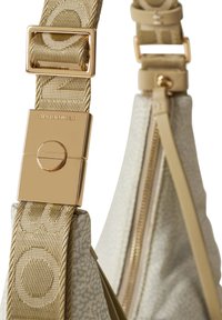 Hellbeige Tasche Riemen mit strukturiertem Muster, ausgestattet mit einer goldfarbenen Metallschnalle und -verschluss, sowie einem Reißverschlussdetails an der Seite.
