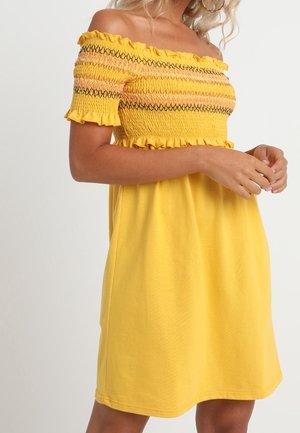 Keltainen olkaimeton mekko, jossa on röyhelöhihoja, tekstuurillista smokkia ja rento istuvuus, oransseja ja mustia vaakasuoria raitoja.