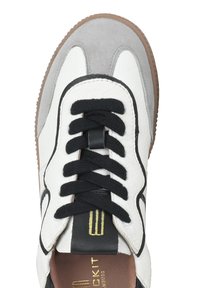 Sneaker bianco in pelle con dettagli in suede grigi, lacci neri e suola in gomma beige. Presenta un logo prominente sulla linguetta e sul lato.