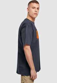 Dark gray short-sleeve t-shirt with orange text design. Straight fit with a soft cotton texture. Side view.