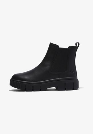 Stivale Chelsea in pelle nera con pannelli laterali elasticizzati, punta arrotondata e suola in gomma spessa con texture rigata e un tab per il sollevamento.