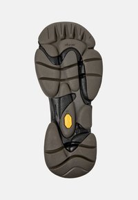 Vibram batų padas su tekstūruotu pilkos ir juodos gumos sukibimu bei geltonu Vibram logotipu centre.
