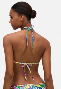 Top de bikini multicolor con patrones florales, diseño de cuello halter, atado por detrás con tiras finas; textura de tejido suave.