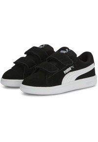 Zapatillas de ante negro con acentos blancos, que presentan una puntera redondeada, dos correas de velcro para el cierre y un collar acolchado para mayor comodidad.