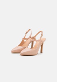 Nude lakované lodičky na podpatku s špičatou špičkou, tenkým páskem kolem kotníku a 10 cm stiletto podpatkem. Hladký, lesklý povrch.
