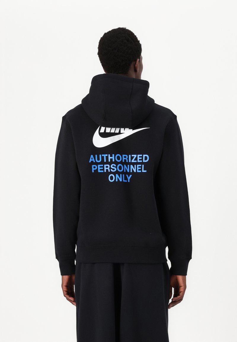 Felpa nera con cappuccio e grande logo Nike bianco, con il testo blu "PERSONALE AUTORIZZATO SOLO" sulla schiena. Materiale in cotone, vestibilità rilassata.