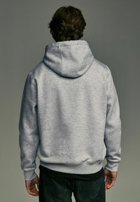 Gray hooded sweatshirt with a smooth texture, featuring a large, adjustable hood and ribbed cuffs, viewed from the back.
