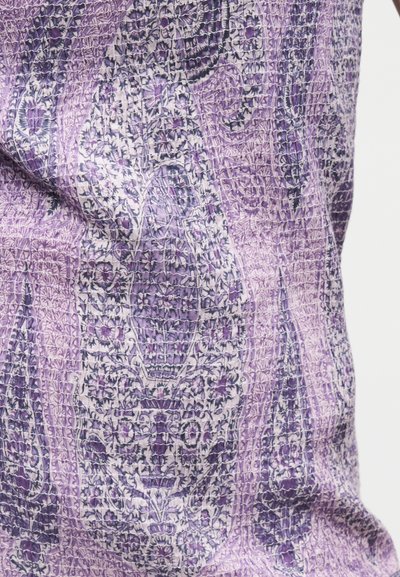 Tissu à motifs floraux violet et blanc avec des points de matelassage complexes créant un effet texturé et froissé.