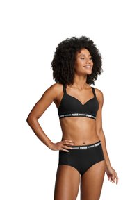 Zwarte sportbeha met een V-hals ontwerp en verstelbare bandjes, gecombineerd met hoge zwarte broekjes met een merkembleem op de tailleband.