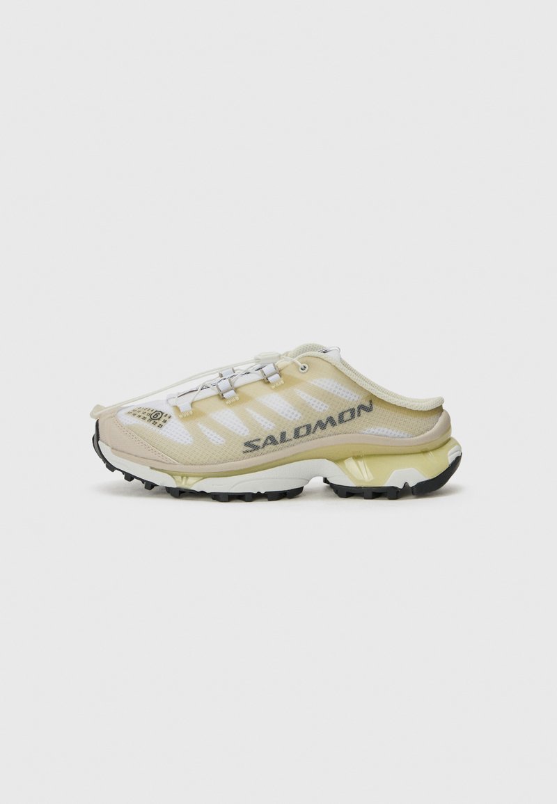 Salomon shoe in light yellow and white mesh with grey accents, a distinctive curved shape, and a textured rubber sole with deep lugs.