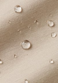 Water droplets beading on beige textured fabric, illustrating water-resistant or waterproof material properties.