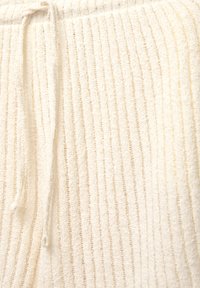 Crème-kleurige loungewear gemaakt van een textuurstof, met verticale ribbels en een tailleband metkoord voor een comfortabele pasvorm.