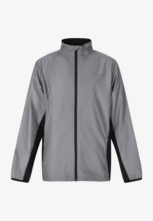 Lettere grå jakke med høj krave, fuld lynlås, sorte sidepaneler og en glat, skinnende overflade. Har et logo på brystet.