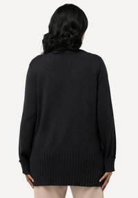 Mörk marinblå långärmad stickad cardigan med ribbad nederkant och ärmar, slät textur och en avslappnad passform, med en medellång design.
