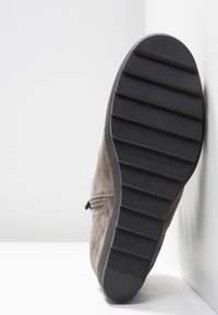 Stivale alla caviglia in suede grigio con superficie texturizzata, zip laterale e suola in gomma con scanalature orizzontali per una migliore trazione.