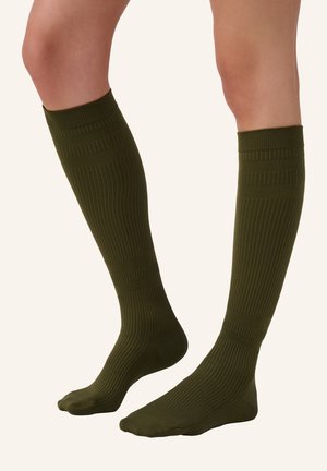 Kniehoge olijfgroene sokken met een geribbelde textuur en horizontale strepen nabij de bovenkant, gemaakt van rekbaar, ademend materiaal.